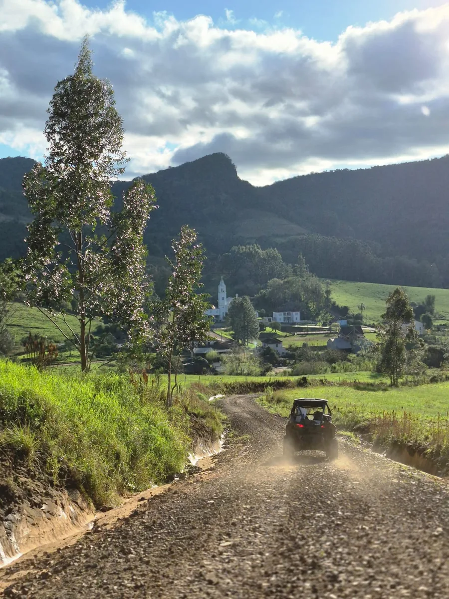 Estrada de chão descendo para o vale, com o povoado e a serra ao fundo